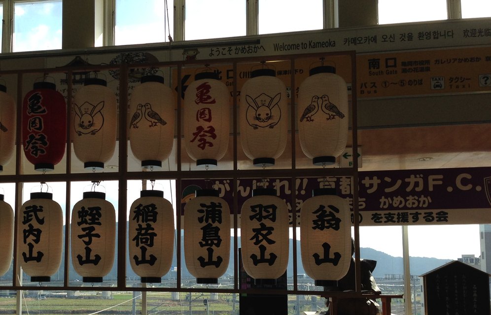 亀岡駅の中に下がる亀岡祭の提灯と、南口の湯の花温泉・バスのりばの案内板（2014年10月撮影）